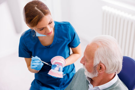Doctor showing jaw x-ray on tablet computer to patient sitting in dental chair at dentist office
