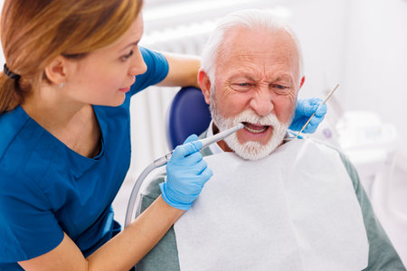 Dentist explaining necessary procedures to patient sitting in dental chair while looking at jaw x-ray at stomatology clinicの写真素材