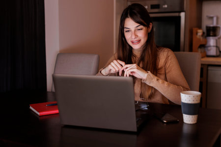 Beautiful young woman sitting in bed, relaxing at home in the morning, wearing headset listening to...