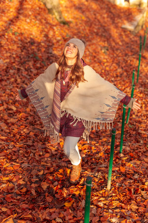 Beautiful young woman having fun spending sunny autumn day outdoors walking through a forest,...