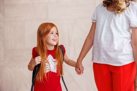 Mother holding hands with her little daughter while taking her to school - first grade student and first day of schoolの写真素材