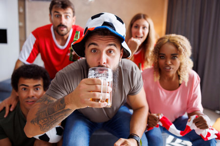 Group of cheerful friends football fans having fun cheering, drinking beer and watching world...