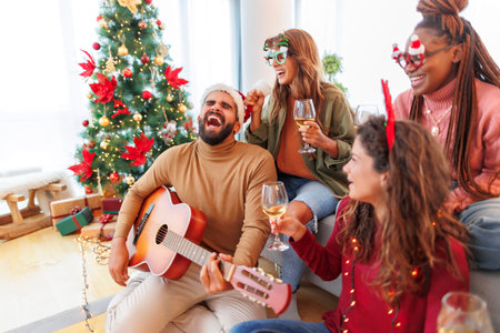Group of young friends drinking wine, laughing and having fun while celebrating Christmas day at home togetherの写真素材
