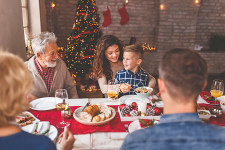 Beautiful happy family gathered around the table, having Christmas dinner all together at homeの写真素材