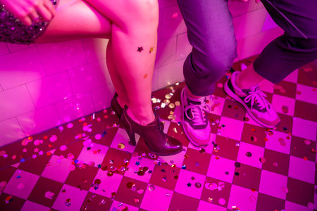Cheerful young couple having fun at New Year's Eve party, holding numbers 2023 while sitting in a...