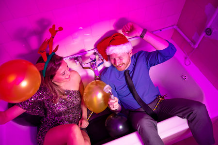 Beautiful young couple in love having fun at New Year's Eve party, singing, dancing and waving with sparklers for midnight countdownの写真素材