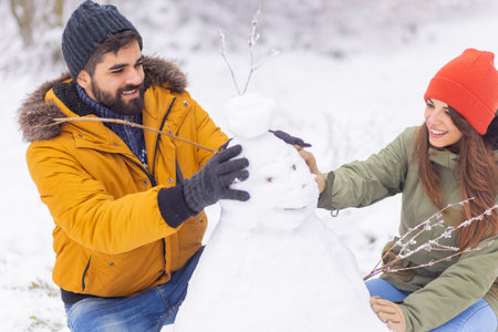 Couple having fun spending winter vacation in the mountains, spending snowy day outdoors, girlfriend pulling boyfriend on sledgeの写真素材