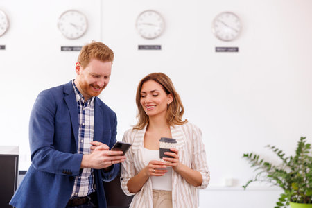Business colleagues having fun using smart phone at the office during a coffee breakの写真素材