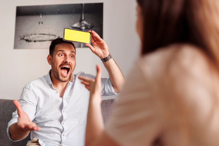 Couple having fun at home playing word guessing game, explaining and guessing the words from a smart...