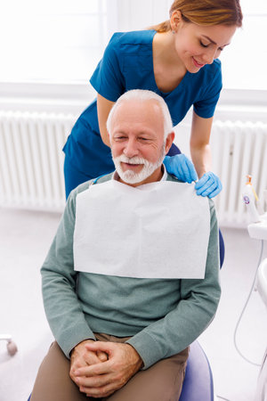 Senior man at dentist office sitting at dental chair ready for checkupの写真素材