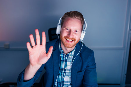 Businessman sitting at his desk wearing headset having online meeting while working late in an...