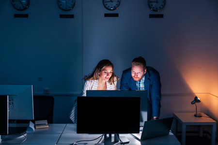 Business colleagues working in an office late at night, reviewing documents and collaborating on new projectの写真素材