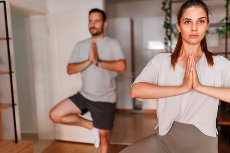 Young couple working out together at home, practicing yoga as morning exercise routineの写真素材