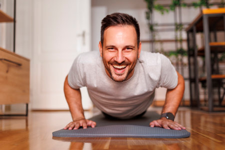 Handsome active man working out at home, doing push ups on yoga mat; man exercising at home in the morningの写真素材