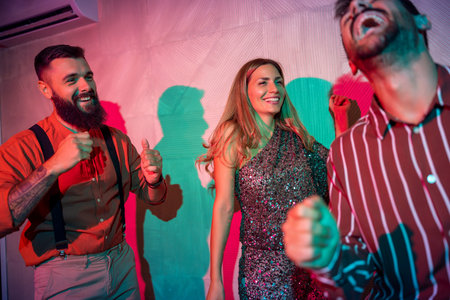 Group of cheerful young friends having fun dancing and singing at New Year's Eve partyの写真素材