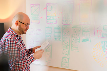 Casual mid 30s man preparing notes for project presentation on seminar or office meeting while...