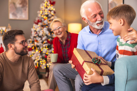 Happy multi-generation family spending Christmas day together at home, son visiting parents with his...