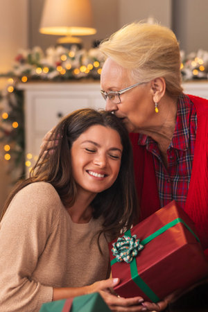 Beautiful mother and daughter exchanging Christmas presents and enjoying spending winter holiday...