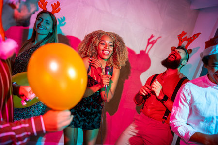 Group of cheerful young friends having fun singing karaoke and dancing at New Year Eve party
