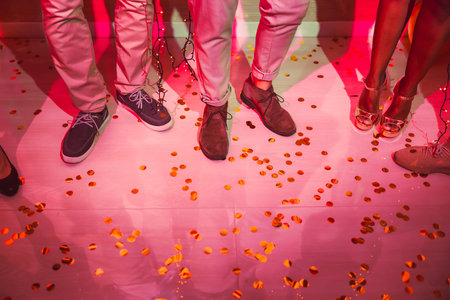 Detail of people's legs while dancing at New Year's Eve party with lots of confetti on the floorの写真素材