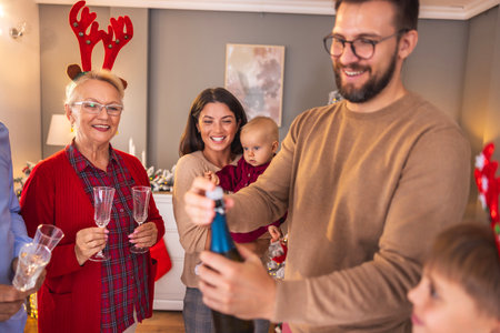 Beautiful happy multi-generation family having fun celebrating New Year at home, man opening a bottle of champagneの写真素材