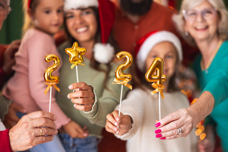 Beautiful happy multi-generation family celebrating Christmas at home, having fun holding little balloons shaped as numbers 2024, representing the upcoming New Yearの写真素材