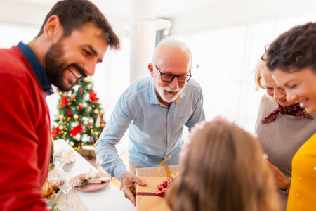 Beautiful happy family gathered at home for Christmas celebration, enjoying their time together and exchanging Christmas presentsの写真素材