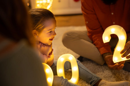 Young parents having fun spending New Year's Eve at home playing with their little daughterの写真素材