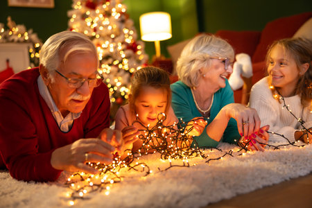 Beautiful happy family having fun celebrating Christmas at home, grandparents spending time with grandchildren lying on the floor by the Christmas treeの写真素材