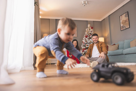 Young parents having fun playing with their toddler boy while spending Christmas day together at...