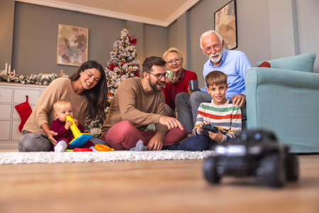 Happy multi-generation family having fun spending Christmas day together at home, father teaching son how to play with remote controlled toy carの写真素材