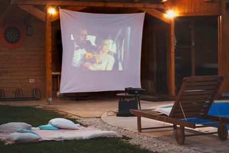 Detail of summertime home open air cinema by the swimming pool with film screening on poolside projector screenの写真素材