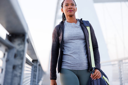 Active woman in sportswear carrying gym bag while going for morning jogging or outdoor workout sessionの写真素材