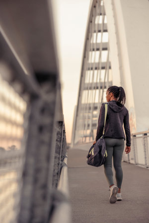 Active woman in sportswear carrying gym bag while going for morning jogging or outdoor workout sessionの写真素材