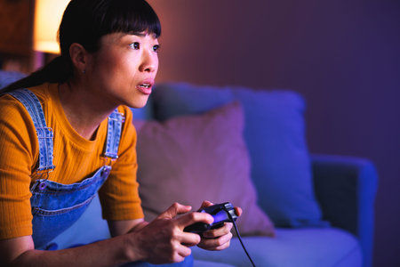 Beautiful young woman having fun playing video games at home late at night, relaxing and enjoying...