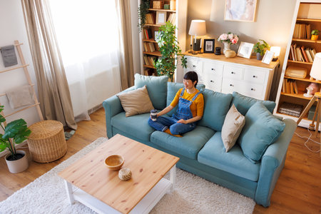 High angle view of beautiful Asian woman relaxing and drinking coffee while enjoying leisure time at homeの写真素材