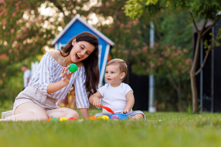 Beautiful young mother having fun playing with her toddler son while on a picnic in the park on summer afternoonの写真素材