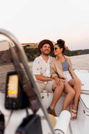 Beauitful young couple in love hugging and relaxing while sailing on a boat just after sunset, enjoying their summer vacationの写真素材