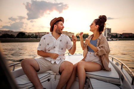 Beauitful young couple in love having fun singing and dancing while sailing on a boat, enjoying city break  summer vacationの写真素材