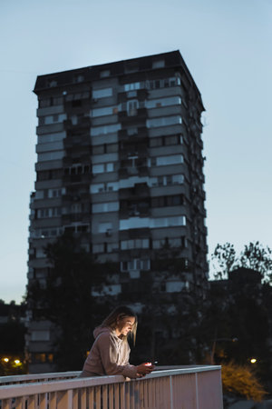 Active young woman using smart phone before jogging at dawn before sunrise early in the morningの写真素材