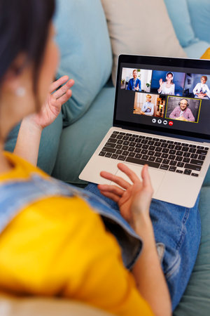 Woman having online meeting using laptop computer while working remotely from homeの写真素材