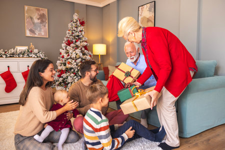 Happy multi-generation family gathered at home on Christmas day, exchanging Christmas presents and enjoying spending time together during winter holiday seasonの写真素材
