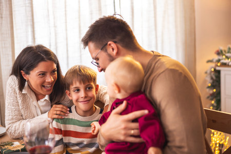 Happy young parents having Christmas dinner with their children - family gathered for winter...