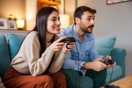 Beautiful young couple in love having fun playing video games while relaxing and enjoying spending...