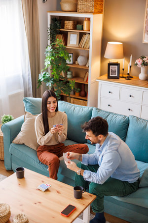 High angle view of beautiful young couple in love having fun playing card games while relaxing and enjoying leisure time at homeの写真素材