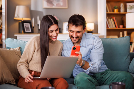 Couple of vloggers working together at home editing and getting ready to post their new video online to social networksの写真素材