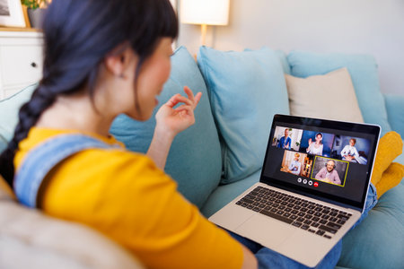 Woman having online meeting using laptop computer while working remotely from homeの写真素材