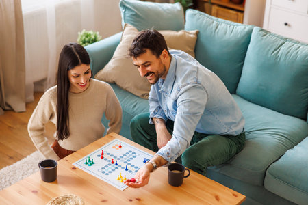 High angle view of beautiful young couple in love having fun playing ludo board game while relaxing...