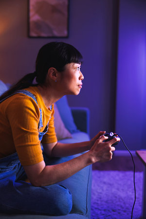 Beautiful young woman having fun playing video games at home late at night, relaxing and enjoying...