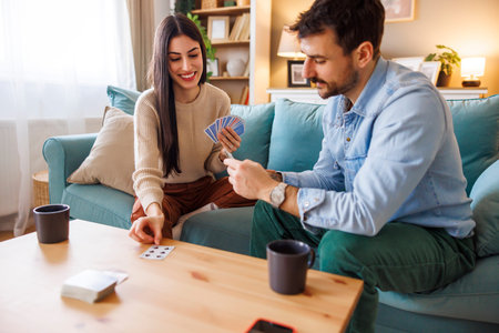 Boyfriend and girlfriend having fun playing card games while relaxing and enjoying leisure time at...